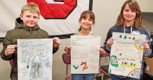 Third graders Emmett Shaffer, Makenzie Anderson, and Harper Rudy showed the posters that they made in science class to the school board, explaining what adaptations different animals would have to make if they were moved to a new habitat.