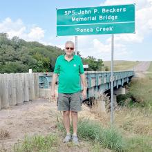 John’s brother Bill, who also served in Vietnam, is shown here next to the sign designating the bridge has been named in honor of his brother.