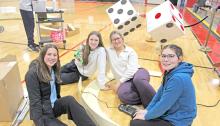 Regan Graesser, Adelyn Veskrna, Allison Walker, and Lainey Dobson build an arch with cardboard and hot glue.