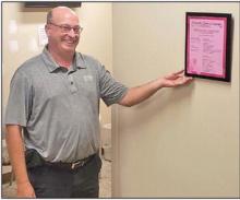 Kelly Meiners, representing First Fidelity Bank of Winner, hangs the Driven to Serve Campaign plaque.
