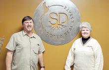 Greg and Sandy Smith stand next to a sign designed and given to them by two of their daughters, the logo for their business and an expression of their ties to South Dakota.
