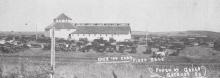 One copy of this photo was dated 1921. The handwritten caption says, “Over 100 cars, first sale.” The sign on the roof identifies the building as Gregory County Sales Pavilion Company.