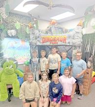 Fourth graders pose in front of the Gregory School Library’s science tent, part of this year’s dinosaur-themed library decorations. The display takes students back to the Jurassic Period, with dinosaurs roaming around a volcano in the background.