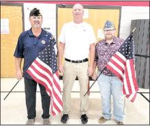 Greg Smith, commander of Hutchison Post #6 American Legion in Gregory, and Aric Hamilton, treasurer for the Gregory chapter of the Sons of the American Legion, presented new American flags to Principal Jeff Determan and the Gregory School District for all of the classrooms in the school building. Hutchison Post #6 and the Sons of the American Legion donated the flags so that every classroom in the building will have a new flag for display.