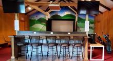 The bar overlooks the golf screen, providing seating as golfers wait their turn. Numerous outlets not only let customers charge their devices, but also come in handy for crockpots if the facility is used for a potluck or party.