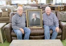 Tom, right, and Jeff, left, pose with a picture of their father, Walter Schramm. A legendary business closes in Winner after 75 years.