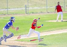 Aiden Frasch tries to avoid a tag by the catcher as his coach (dad) “helps” on the third base line. (Photo by Sara Anderson)