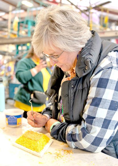Volunteers complete the painstaking work of gluing corn kernels on one at a time.