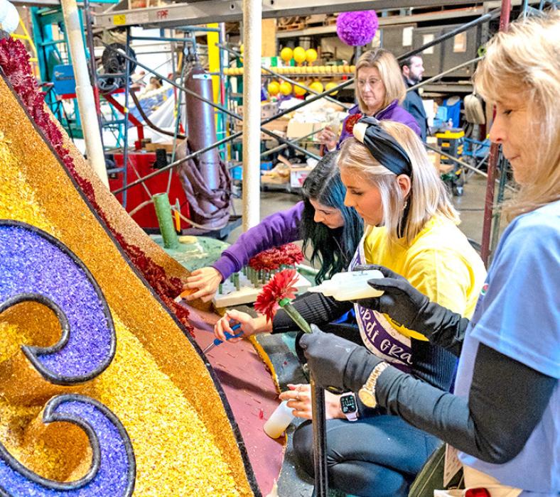 Volunteers poke holes and glue in water-tubed flowers on the float.