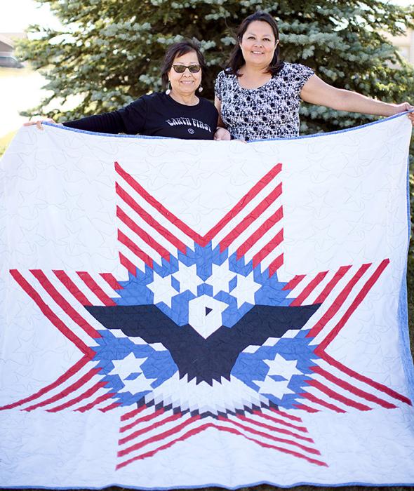 Wilma, l, and Lisa show the star quilt made by Wilma’s mother, Velda Bearshield, that incorporates an eagle into the star design. Velda made the quilt when her son, Willie Bearshield, was in Desert Storm. (Photo from Quiltfolk, used with permission)