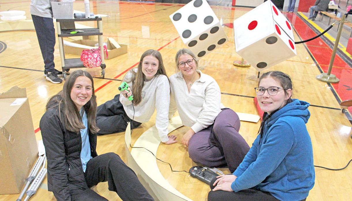 Regan Graesser, Adelyn Veskrna, Allison Walker, and Lainey Dobson build an arch with cardboard and hot glue.