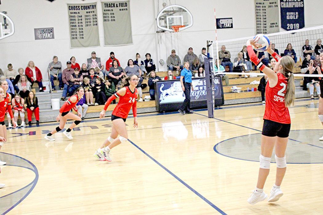 Adelyn Veskrna sets the ball as Regan Graesser and Aubree Miller approach the net.