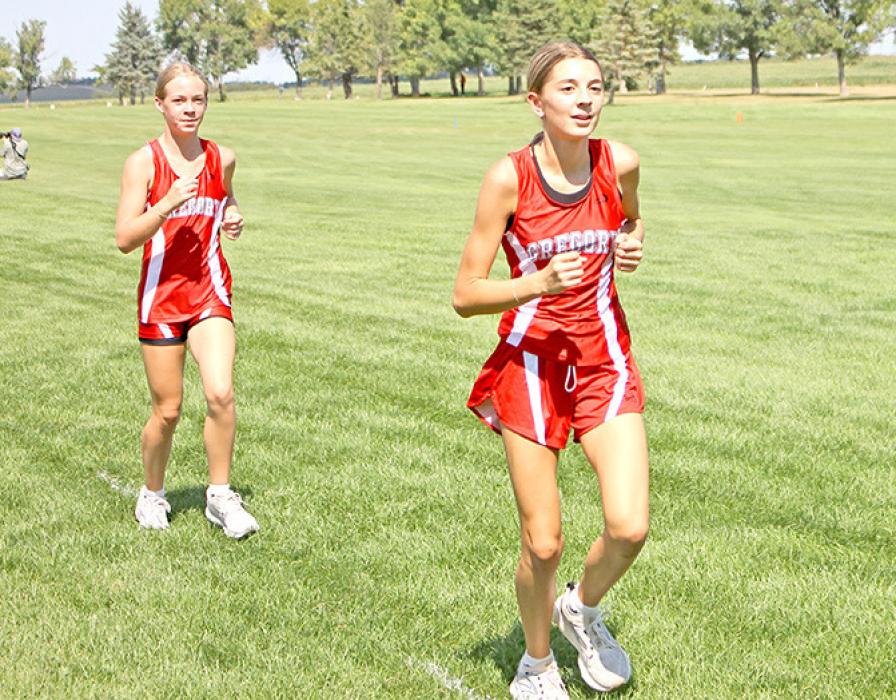 Seventh graders Mya Warnke and Avery Birkel, l to r, ran on the girls varsity team at the Gregory Cross Country Meet on September 2, 2025. Avery finished 11th with a time of 26:30.18, and Mya came in 16th with a time of 28:00.06 behind their teammate Abigail Engel, who finished second. (Photo by Hayden Odegard)