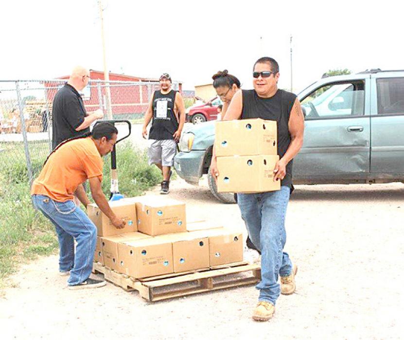 Volunteers help unload boxes of food for children across the Pine Ridge Reservation as part of a summer food program.