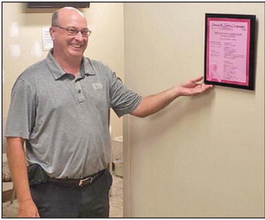 Kelly Meiners, representing First Fidelity Bank of Winner, hangs the Driven to Serve Campaign plaque.