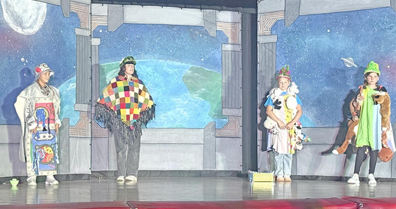 On Friday, July 24, 2026, local youth performed Space Pirates! at the Gregory Memorial Auditorium. From left to right; robot, Brenlee Braun, Edie from Theatre 605, and alien interns — Paisley Graber and Jessa Bartling.