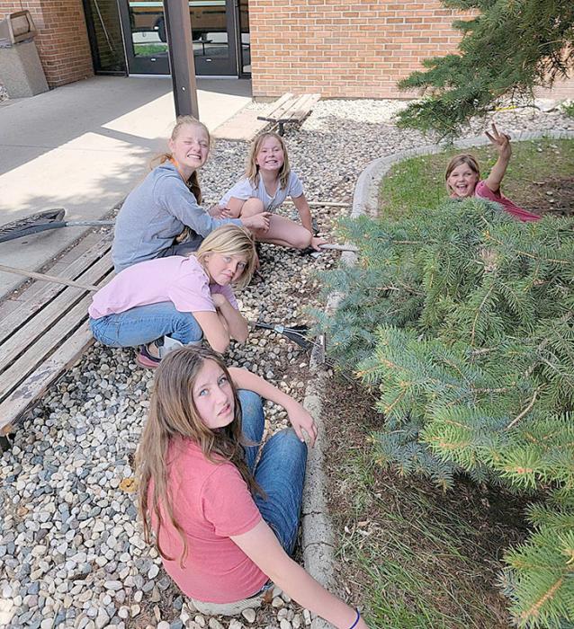 Members of the junior class planted flowers in the base of solar lanterns at the hospital and nursing home. Below, the fourth graders helped clean up around the school, thinning the planters and moving rocks where they belong.