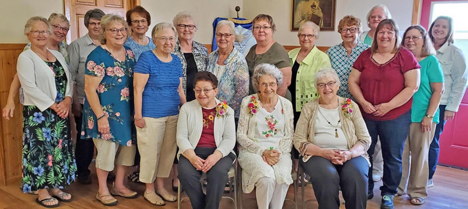 Members present for the jubilee celebration gathered for a photo. Standing, l to r: President Barb Fenenga, Rita Grim, Bev Rubel, Jackie Layh, Joann Eliason, Marlene Smutny, Carol Odenbach, Darlene Shattuck, Marijane Fulwider, Cheryln Shaffer, Darlene Opperman, Kari Kerner, Polly Breithaupt, Joyce Vakiner, and former extension agent Betsy Heyden. Seated, l to r: Elaine Nemer, Cathy Wernke, and Kathy Kayl.