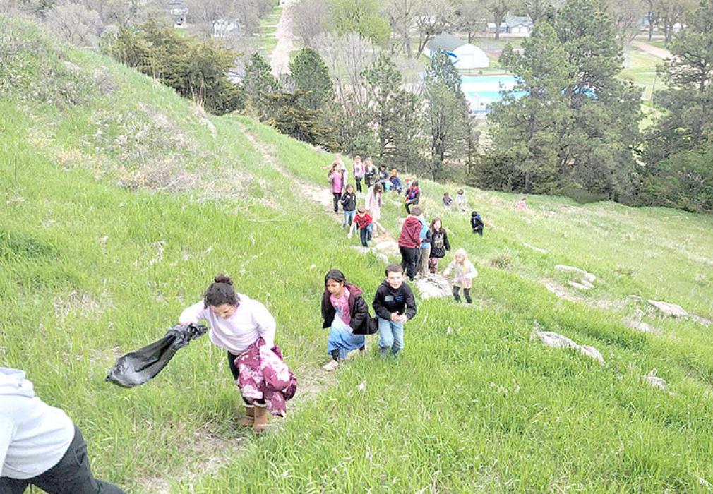 Second graders scale a trail at the buttes in the park to pick up sticks and garbage.