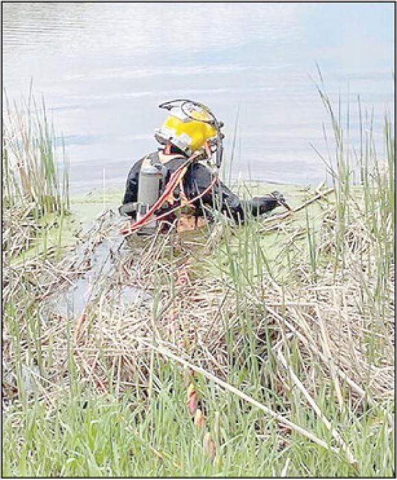 A diver wades into the water at the golf course to repair the intake to the sprinkler system. They often work in murky waters where visibility is limited to only a few inches.