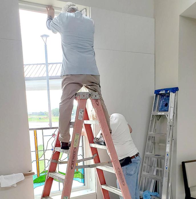 Stained glass artist Michael Pilla (on the ladder) measures the opening of the window with help from his assistant Jim Colvin.