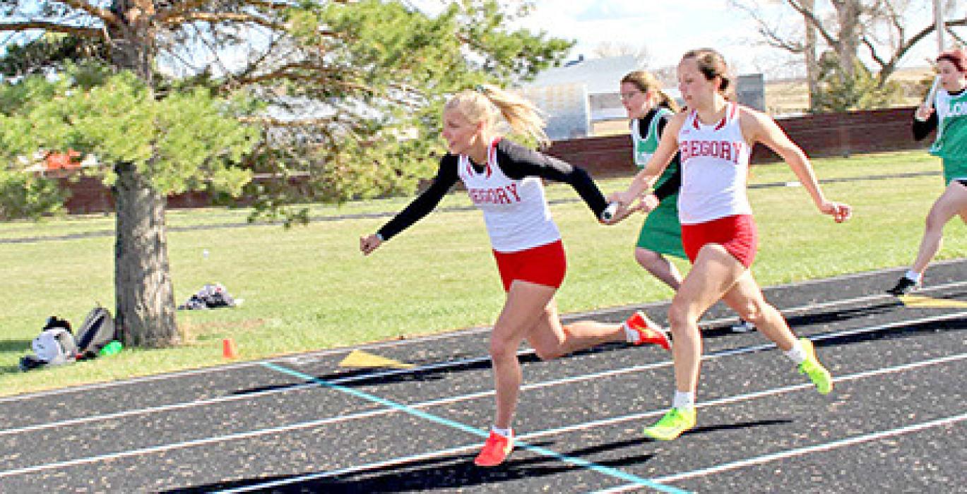 Abby Holmes passes the baton to Ashlyn Vosika in their winning effort in the girls 4x100 meter relay. (Photo by Lesley Atkins)