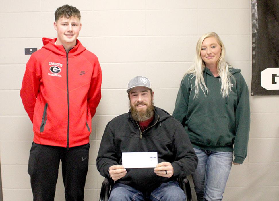 Cruz Klundt, the student body president presenting a check to Justin Weiss and Ashley Sengelmann.
