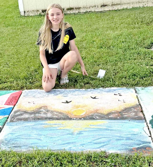 Kylie Schell beams in front of her winning sidewalk square, a detailed nature scene, that captured the hearts of voters in the Fourth of July Art Walk competition.