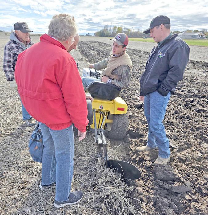 Kenny Roggow, Rita Grim, Byron Grim (behind Rita), and David Misener offer advice to Jack Schulte on the lawn tractor.