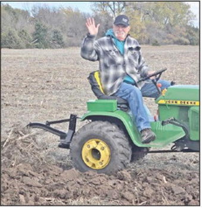 Wes Schell offers a friendly wave as he plows a straight row in the lawn tractor plow days event.