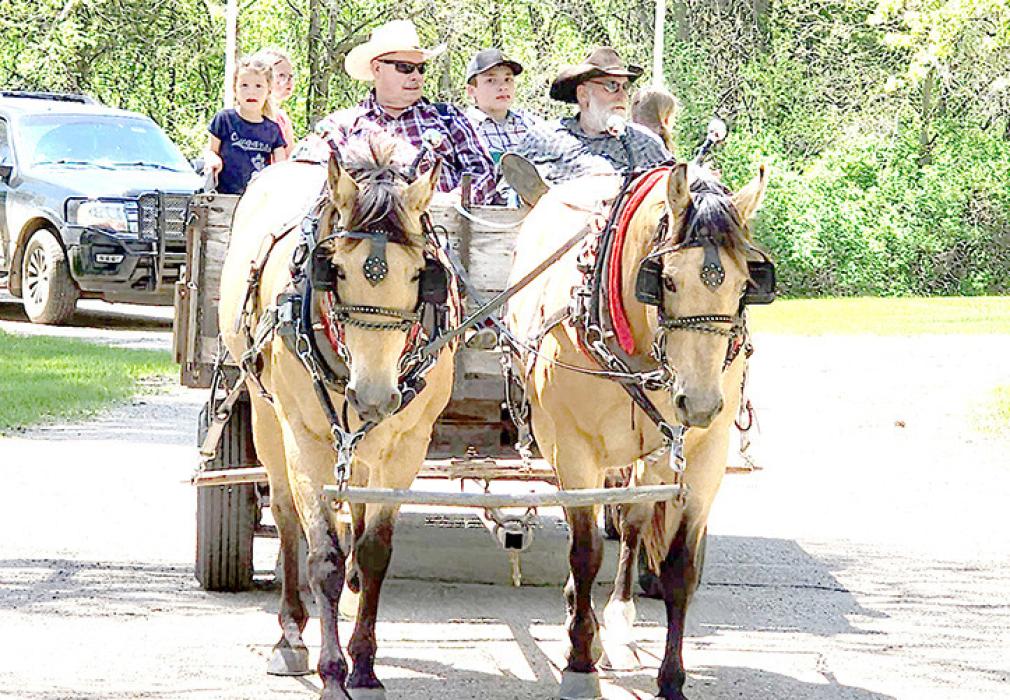 Bruce Boes and Leroy Miller give rides on horse drawn wagon.