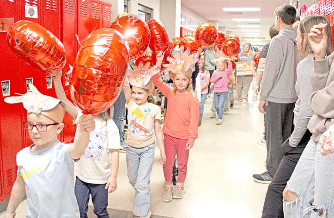 The kindergarteners donned turkey hats as they carried their crab balloons.
