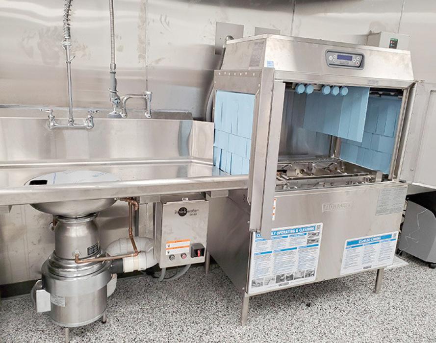 The new dishwasher can wash 200 trays of dishes in one hour, running them through on a conveyor belt.