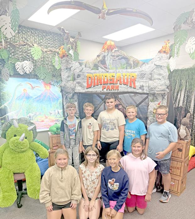Fourth graders pose in front of the Gregory School Library’s science tent, part of this year’s dinosaur-themed library decorations. The display takes students back to the Jurassic Period, with dinosaurs roaming around a volcano in the background.