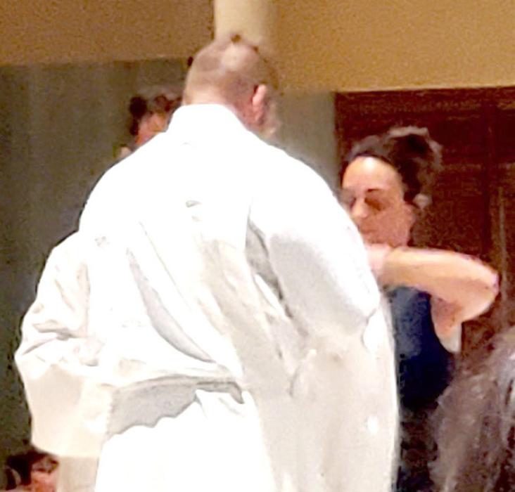The wives, along with their parish priests, assist with vesting the new deacons. This shows their support for their husbands in their new roles.