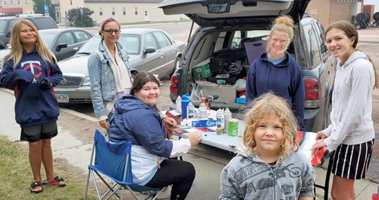 Assisting Cary Thrall (second from left) with the Linking Fences art project on the Gregory Daycare fence were art assistants Sierra Smith (seated at table), Patience Swift and Adelyn Veskrna (standing, to the right). Also helping that day were Maric Klinger (far left) and Keya Klinger (front).