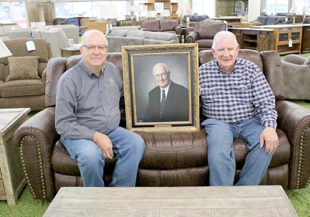 Tom, right, and Jeff, left, pose with a picture of their father, Walter Schramm. A legendary business closes in Winner after 75 years.