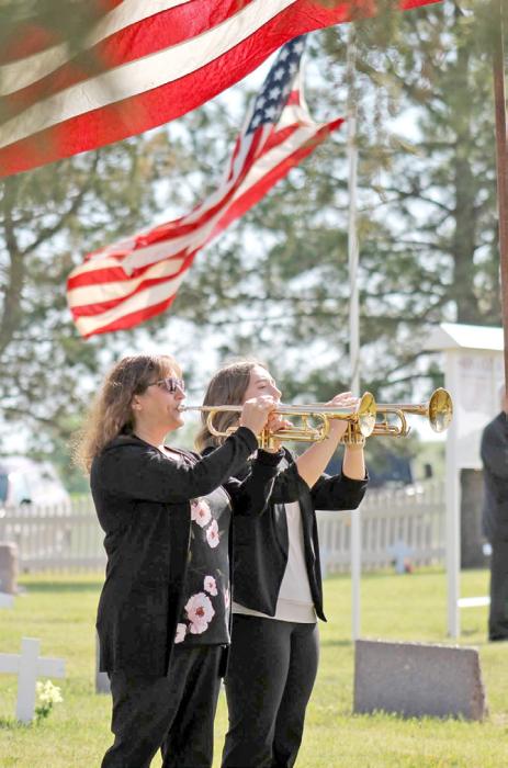 Community members gather at the Iona Cemetery. Michelle and Jaelyn Birkeland performed “Taps.” (Jenifer Hoeft)