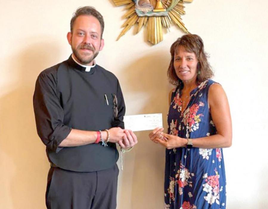 Fr. Jonathan Dillon, pastor of St. Joseph Catholic Church in Gregory, is shown presenting a $1000 check on behalf of the church for the new swimming pool to Kellie Stukel, one of the fund drive’s organizers.