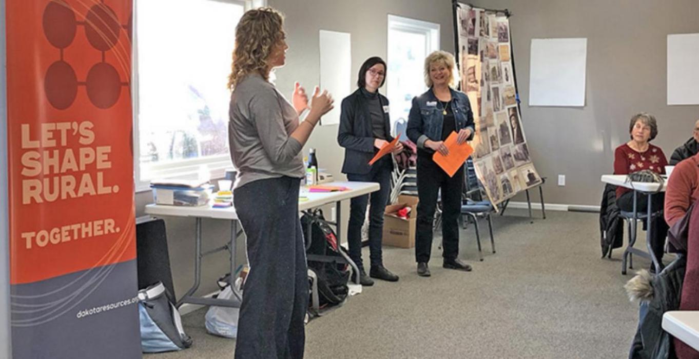 Dakota Resources coaches Jamie Horter and Kristi Wagner stand by as community leader Kelsea Kenzy Sutton addresses the group at the Gregory County Community Gathering in February 2020.
